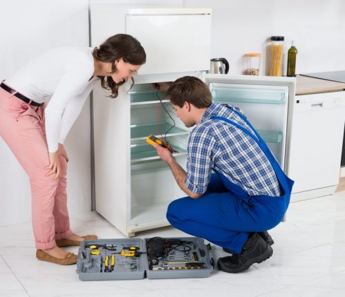 Beautiful,Housewife,Looking,At,Male,Worker,Repairing,Refrigerator,In,Kitchen