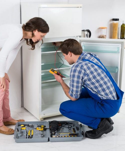Beautiful,Housewife,Looking,At,Male,Worker,Repairing,Refrigerator,In,Kitchen