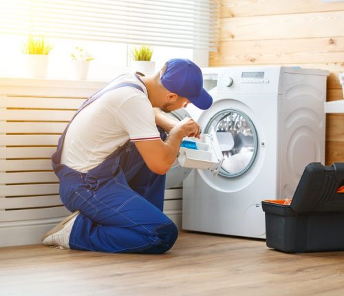Working,Man,Plumber,Repairs,A,Washing,Machine,In,Laundry