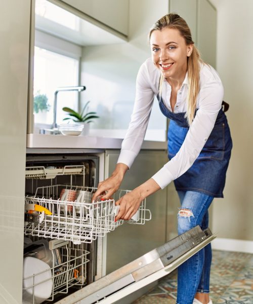 Young,Blonde,Woman,Smiling,Confident,Using,Dishwasher,At,Kitchen