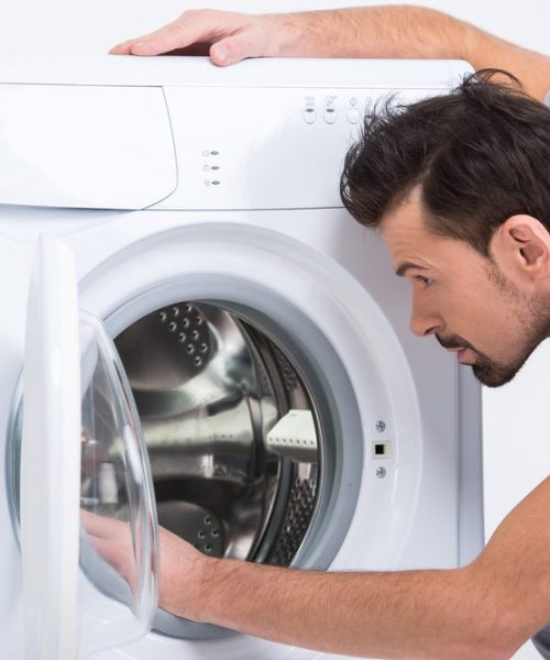 Repairman,Is,Repairing,A,Washing,Machine,On,The,White,Background.
